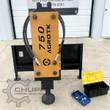 AGROTK 750 post driver standing upright on its quick-attach plate, domed cup down, hoses coiled, hardware case beside it