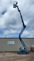 Genie Z-40/23N articulating boom lift, boom telescoped upward against a cloudy sky