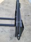 Pallet fork carriage top rail with the sleeved hydraulic hose run zip-tied along it, forks at left