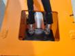 Two sleeved hose ends bolted inside the orange top-plate opening, cylinder rod behind them