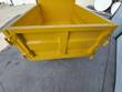 Yellow steel dump bed of the mini dumper, empty cargo box and rear tailgate with latch hooks