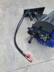 Angle broom's mount plate and angle cylinder with hoses running to red-capped quick couplers