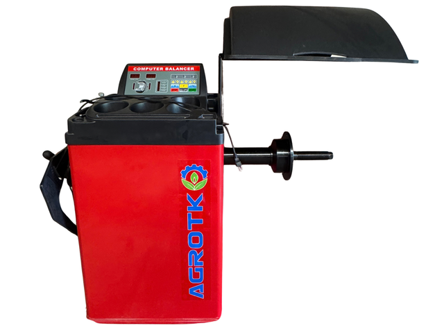 Red computer wheel balancer, side view, raised hood, weight tray, control panel and shaft with cone flange