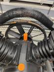 Compressor pump head with orange caps, black pump pulley and drive belt behind the mesh belt guard