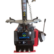 Tire changer front view: turntable with clamps, bead breaker arms, tower with warning labels and three foot pedals