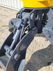 Grapple hydraulic cylinder, hoses and pivot pins on a gray tine arm below the yellow rotator