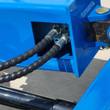 Blue auger drive frame with two spiral-wrapped hydraulic hoses running to threaded drive fittings