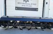 Black skid steer tiller rotor, rows of bolt-on curved tilling blades on the flanged shaft, drive coupling at the end