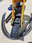 Hydraulic breaker from above: two black hose ports on the mount, hoses coiled to either side