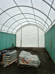 Interior of a container shelter, white fabric roof between two green shipping containers