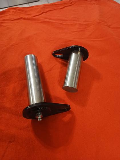 Two hardened steel tilt cylinder pins with black flag plates, one with a grease fitting