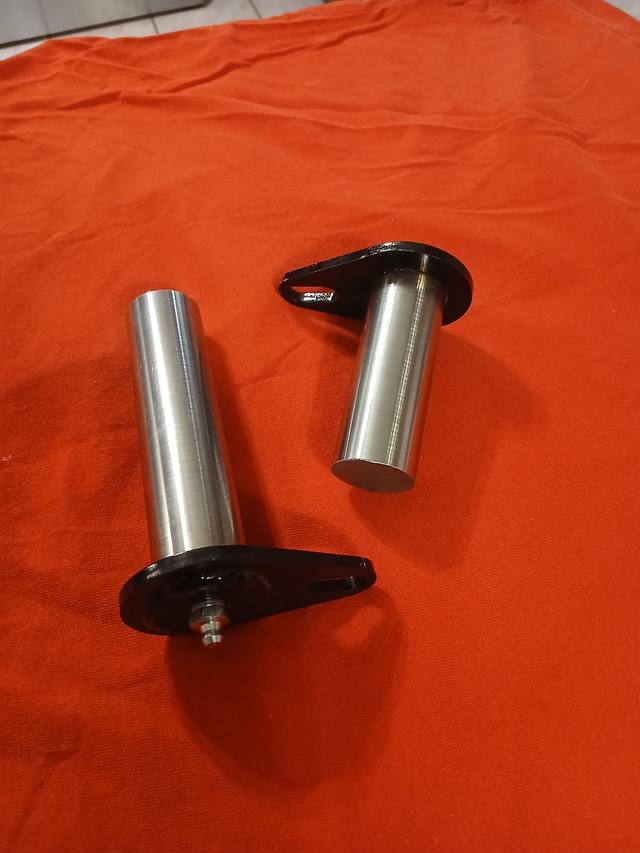Two hardened steel tilt cylinder pins with black flag plates, one with a grease fitting