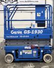 Blue Genie GS-1930 scissor lift fully lowered, guardrails around the platform, ground control panel, non-marking wheels