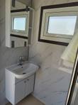 Portable restroom interior: white corner sink and vanity cabinet, chrome faucet, mirrored cabinet, marble-look wall panels