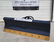 6-way dozer grading blade, front view: black moldboard, bolt-on yellow cutting edge and hydraulic hoses on top