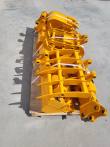 Yellow attachment set banded to a pallet, grapple and rake tines over a bucket with quick-attach bracket