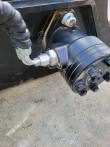 Hydraulic drive motor bolted to the sickle mower frame, steel hard line and hose fitting at the port