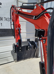 MX15R mini excavator arm with hydraulic thumb clamped over the toothed bucket, work light and hydraulic hoses