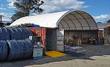 26x40x10 container roof shelter in use: white arch cover spanning two shipping containers over a work area