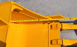 Yellow excavator bucket from above, curved gusset mount with twin pin bosses and bolt-on teeth, tape across