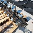 Wolverine trencher digging chain up close: cupped steel teeth bolted to the chain, boom bar and idler sprocket