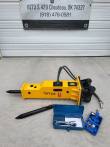 TOFT530 yellow hydraulic breaker standing upright with hoses, spare moil point, wrench box and charge kit