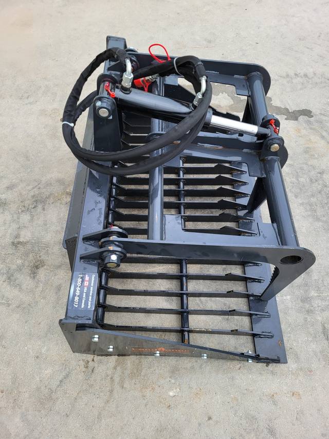 Landhonor rock grapple, spaced steel tines under a hydraulic top clamp arm, hoses coiled over the frame