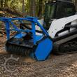 Blue drum mulcher mounted on a tracked skid steer, cutting drum working at ground level