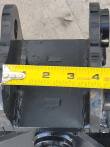 Tape measure hooked on the tilt bucket's mounting bracket ear, reading past 4 inches