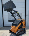 QB-480 mini skid steer, orange Arteer loader on rubber tracks with the dirt bucket raised high on its lift arms