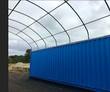 Bare galvanized arch frame of a container shelter mounted on the roof of a blue shipping container