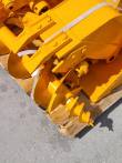 Yellow bucket shells and bolt-on tooth shanks stacked on the pallet with the auger bit alongside