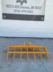 Yellow 46-inch excavator root rake, seven curved tines on a tubular frame with twin pin bosses