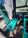 MH13RX mini excavator: teal side console with chrome control levers and rocker switches, AGT-decaled boom alongside