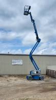 Genie articulating boom lift with the boom raised nearly vertical and the platform high overhead