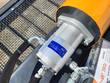 Close-up of the orange hydraulic drive motor and its steel pump housing bolted to the top of the screening bucket.