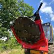 GIYI disc mulcher tilted up on a skid steer, black cutting disc ringed with bolt-on carbide teeth in a red housing