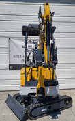 SDLE20 mini excavator head-on with the boom raised, LED work light, canopy and seat, push blade across the tracks