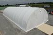 White PVC fabric storage building seen from above: arched ribbed roof and a full-height door at one end
