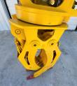 Grapple rotator bearing and mount plate above the curved yellow tines, red tooth tips at the base
