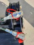 Hydraulic quick couplers with red dust rings and braided hoses at the bucket's clamshell hinge
