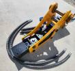 Hydraulic breaker on its side, yellow mount frame with chrome pivot pins, hoses and chisels alongside