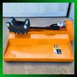Orange Wolverine flail mower with excavator mount bracket and hydraulic motor, green border graphic