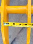 Tape measure across the gap between two of the yellow rake's tines, spanning about four inches