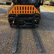 Wolverine 48-inch pallet forks mounted on a skid steer: orange slatted backrest and hydraulic fork-positioning cylinder