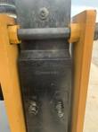 AGROTK 750 post driver hammer body between the yellow mount rails, IN and OUT hydraulic ports, cast markings