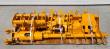 Yellow attachment package banded to a pallet: auger flighting, hydraulic cylinder, buckets and rake tines