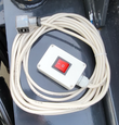 White control switch box with a red on/off rocker, coiled cable and DIN valve connector for the rake