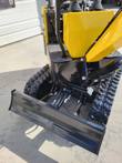 AGT QH12R backfill blade raised on its hydraulic cylinder, between the rubber tracks and undercarriage
