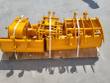 Yellow mini excavator attachment set banded to a pallet: buckets, grapple tines, rake and auger flighting